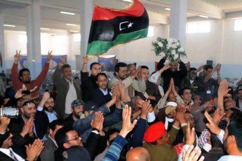 Libyans applaud the the national flag at a meeting of tribal leaders to discuss a semi-autonomous statute for a region in Libya yesterday.