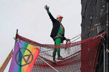 A climate activist dressed as Britain's Prime Minister Boris Johnson gestures after climbing scaffolding and unfurling banners on the Elizabeth Tower, commonly known by the name of the bell, Big Ben on the twelfth day of demonstrations by the climate change action group Extinction Rebellion, in London, on October 18, 2019. AFP / Tolga AKMEN