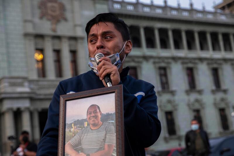 Alex Garcia, 29, cries as he holds a portrait of his father, René García, who died in June 2020, at age 59, of COVID-19, during a tribute organized to honor the thousands of people who died from the disease in Guatemala City. AP Photo