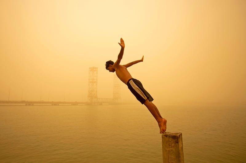A youth dives into the Shatt Al Arab river during a sandstorm in Iraq's southern city of Basra. Another sandstorm in Iraq sent at least 4,000 people to hospital with breathing problems and led to the closure of airports, schools and public offices. AFP