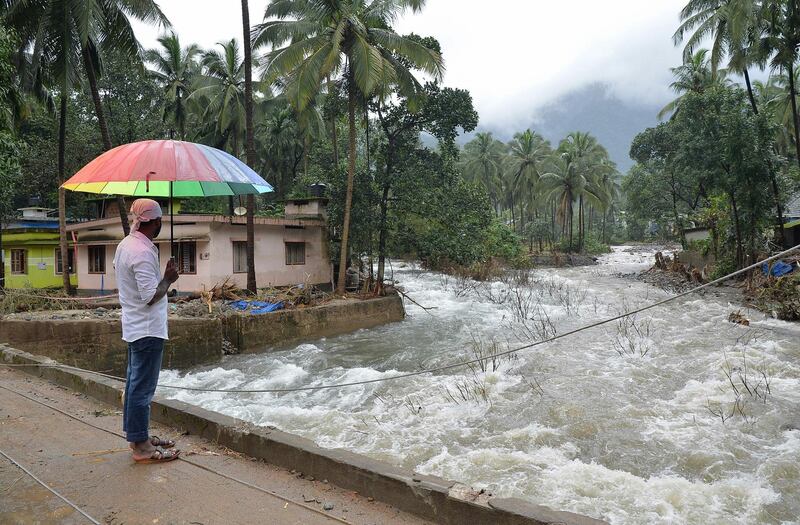 An Indian villager looks at the overflowing Kannappanakundu river in Kozhikode district, about 422 km north of Trivandrum, in the south Indian state of Kerala, on August 18, 2018. - Pressure intensified on August 18 to save thousands still trapped by devastating floods that have killed more than 300 in the Indian state of Kerala, triggering landslides and sending torrents sweeping through villages in the region's worst inundation crisis in a century. (Photo by MANJUNATH KIRAN / AFP)