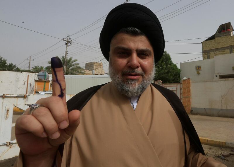Iraqi Shi'ite cleric Moqtada al-Sadr shows his ink-stained finger after casting his vote at a polling station during the parliamentary election in Najaf, Iraq May 12, 2018. REUTERS/Alaa al-Marjani