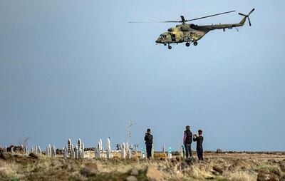 TOPSHOT - A Russian helicopter flies over a joint Russian and Turkish convoy (not pictured) as it patrolls in oil fields near the town of al-Qahtaniyah, in Syria's northeastern Hasakeh province close to the Turkish border, on February 4, 2021.  / AFP / Delil SOULEIMAN
