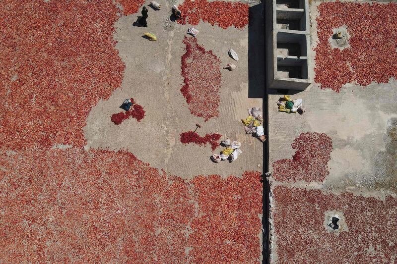 People spreading hot red peppers on a roof to dry to make paste and flakes, in Al Mastumah, Syria. AFP