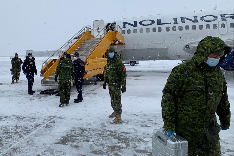 Canadian Forces personnel stand by to assist Canadians evacuated from China as they disembark from a plane at Canadian Forces Base Trenton in Trenton, Ontario, Canada.  Reuters