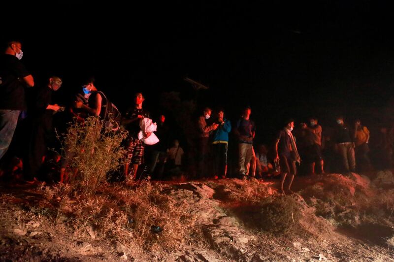 Refugees wearing facemasks gather outside the Moria camp on the island of Lesbos during a major fire there.   AFP