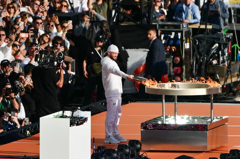 French rapper Julien 'Jul' Marie lights the Olympic and Paralympic Torch Relays cauldron at the Old Port in Marseille. AFP