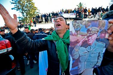 A man chants slogans while holding a portrait of Algeria’s late military chief Lt Gen Ahmed Gaid Salah as people gather outside the Palace of the People for his funeral in Algiers on December 25, 2019. AFP