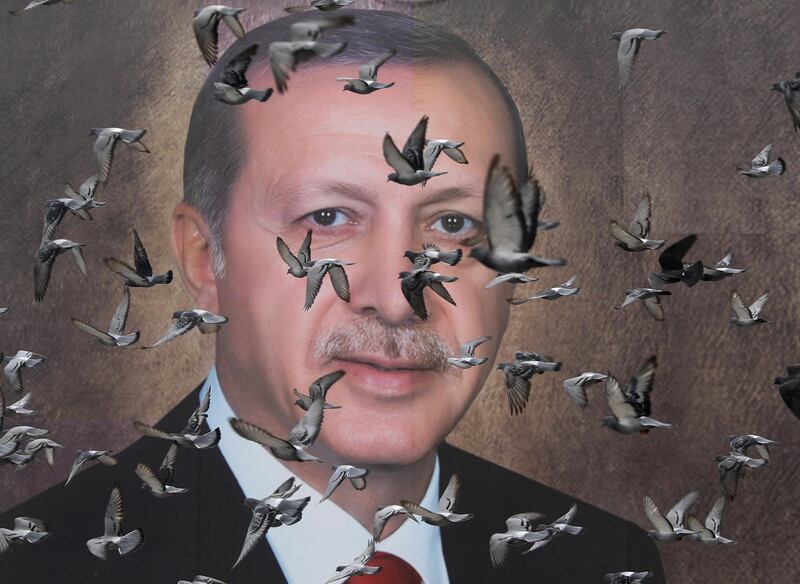Pigeons fly in front of a large poster of Turkish President Tayyip Erdogan in Bursa, Turkey. Reuters