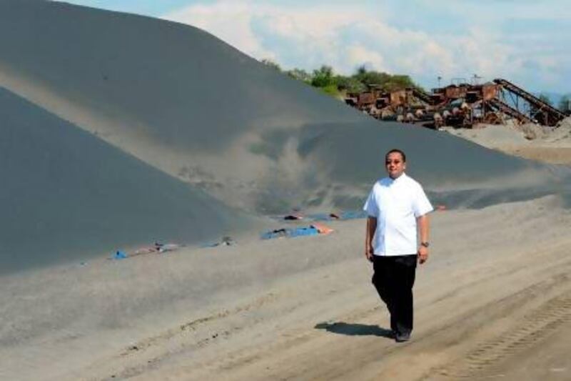 Catholic priest Sammy Rosimo with a pile of fine black sand at an abandoned magnetite or black sand mine site along the coast of Caoayan town, Ilocos sur province, north of Manila.