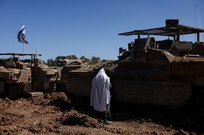 An Israeli soldier praying next to military vehicles near the Israel-Gaza border. Reuters