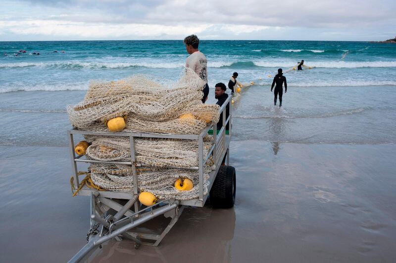Members of the Shark-spotter crew pull in the exclusion net at Fish Hoek beach, a popular swimming and surfing spot in Cape Town. AFP