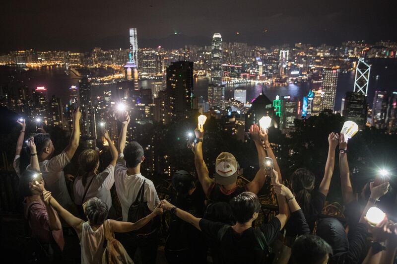 Pro-democracy protesters form a human chain and wave laser pointers, phones and lanterns in the air on Victoria Peak in Hong Kong, China. Getty