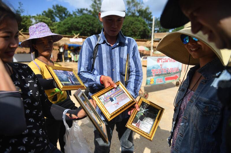 Vendors selling souvenir photos on the road leading to the Tham Luang cave. AFP