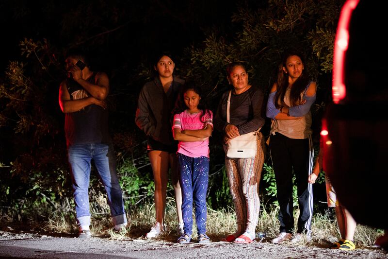 Community members wait on the side of the road at the scene. Reuters