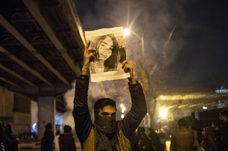 An Iranian man holds a picture of a victim of the Ukrainian Boeing 737-800 plane crash during a demonstration in front of Tehran's Amir Kabir University.  AFP