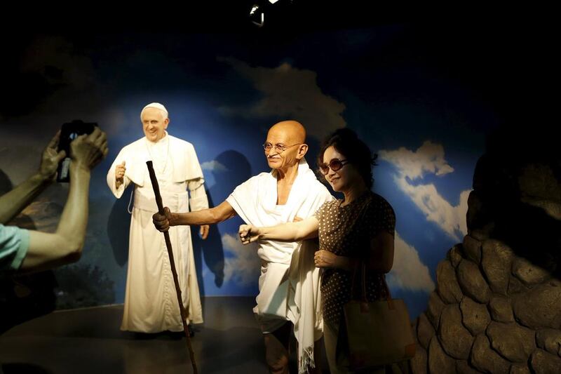 A woman poses for photos on July 30, 2015, with the wax figures of Mahatma Gandhi, centre, and Pope Francis, left, at Grevin Wax Museum in Seoul, South Korea, July 30, 2015. French wax museum Musee Grevin has opened its first Asian branch in central Seoul. Kim Hong-Ji / Retuers