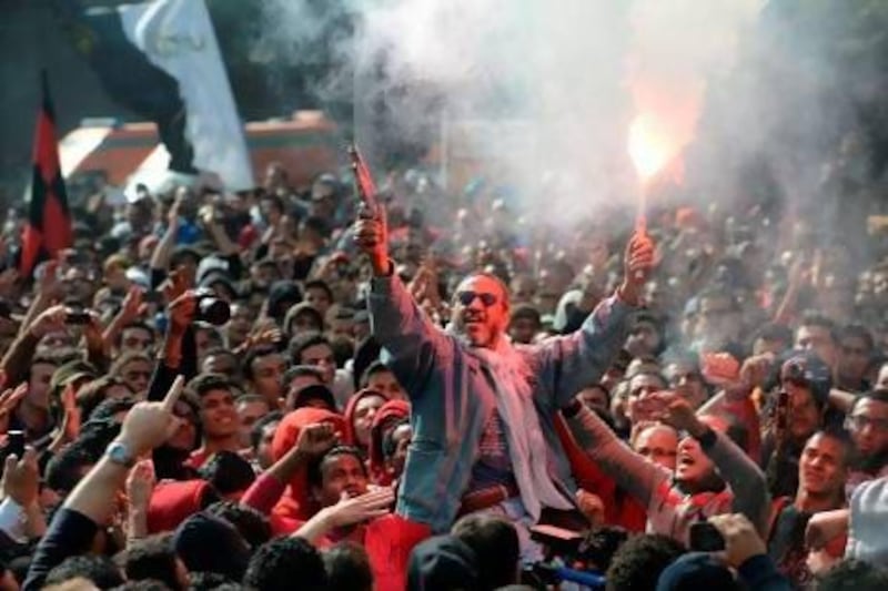 An Egyptian fan of Al Ahly football club fires celebratory shots in the air and lights a flare as club supporters celebrate outside its headquarters in Cairo on Saturday after a court sentenced 21 people to death over a football riot that killed more than 70 people last year. Khaled Desouki / AFP