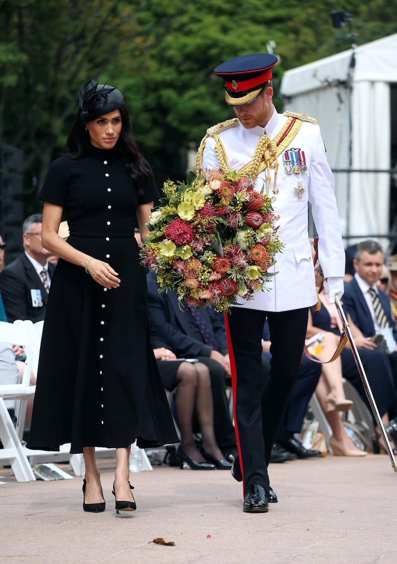 Britain's Prince Harry and Meghan, Duchess of Sussex, carry a floral wreath at the opening of the enhanced ANZAC memorial in Hyde Park, Sydney, Australia October 20, 2018 Reuters