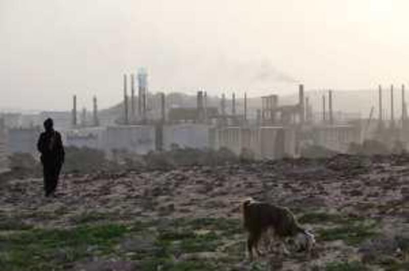 A Bedouin woman walks oposite to the only refinery in Jordan, operated by the Jordan Petroleum Refinery Company (JPRC), east-north of Amman, Jordan. (Salah Malkawi for The National)