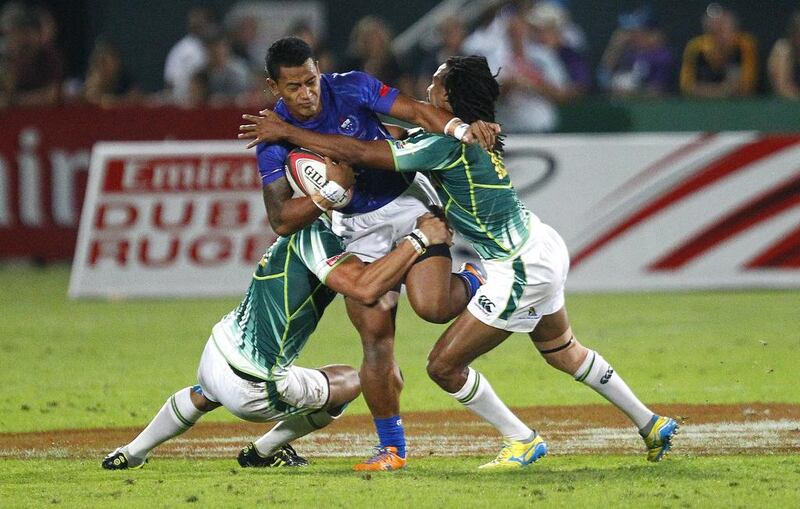 Fale So'oialo of Samoa, centre, is tackled during the Sevens World Series match between Samoa and South Africa on Friday in Dubai. Jake Badger for The National