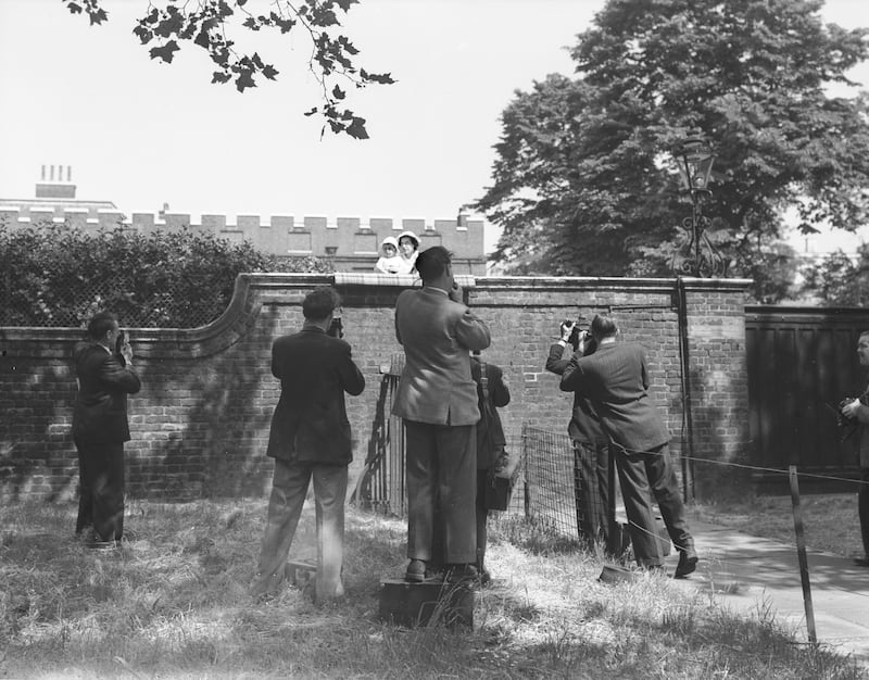 Photographers snap a young Prince Charles as he peers over the wall of Clarence House to watch the procession in 1950