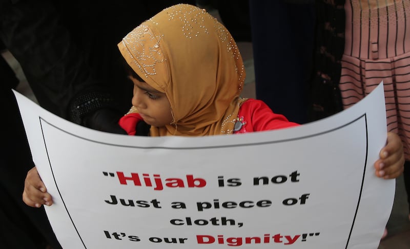 A girl with a placard reading 'Hijab is not just a piece of cloth, it's our dignity'. EPA