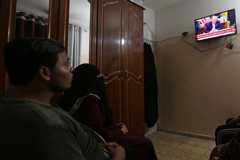 Palestinians watch television screen displaying news on UAE 's agreement with Israel on normalising relations, in the southern Gaza Strip. Reuters