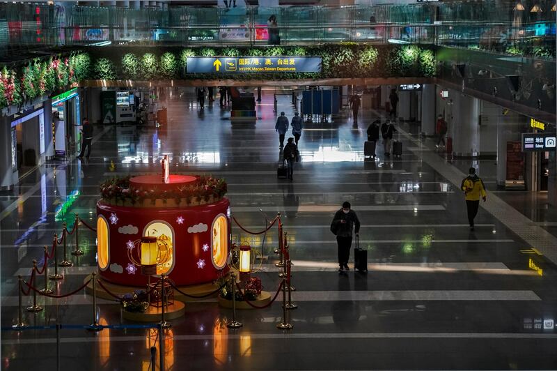 Passengers wearing face masks to curb the spread of the coronavirus walk by a Lunar New Year decoration on display at the departure hall of the Beijing Capital International Airport in Beijing. Amid fears of new variants of the virus, new restrictions on movement have hit just as people start to look ahead to what is usually a busy time of year for travel. AP Photo