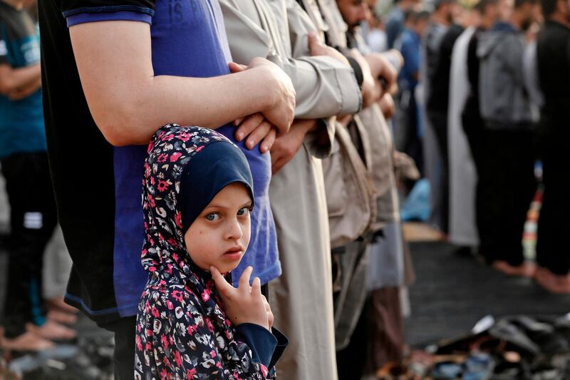 A Palestinian Muslim girl stands next to a relative performing the morning prayer to celebrate Eid al-Fitr in Gaza City. AFP