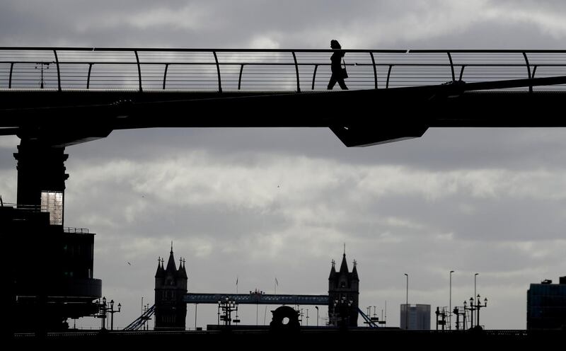 A pedestrian walks across the Millennium Bridge over the River Thames in London, the day after Prime Minister Boris Johnson announced plans to let more people go to work. AP