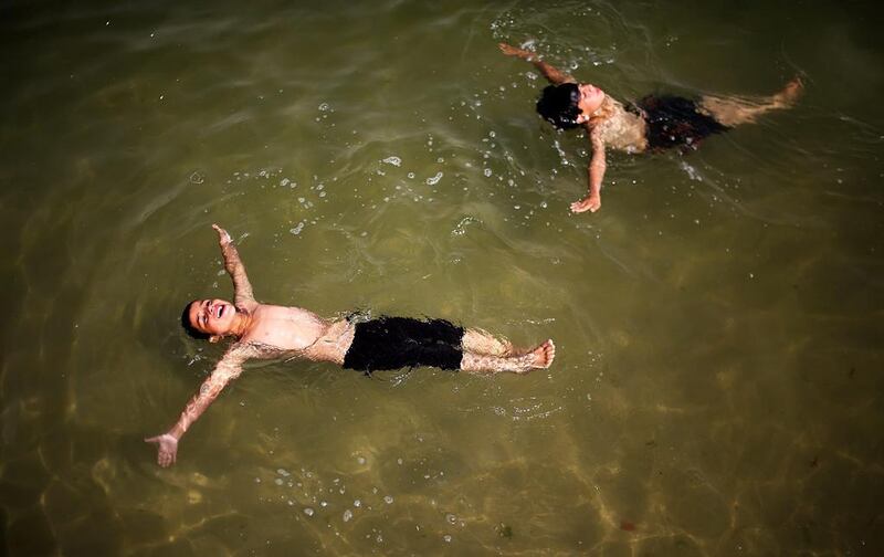 Two Palestinian brothers Mamud, 10, (R) and Wassem, 8, Reasha (L) enjoy their time in the Gaza beach during a hot weather in the west of Gaza City. Mohammed Saber / EPA