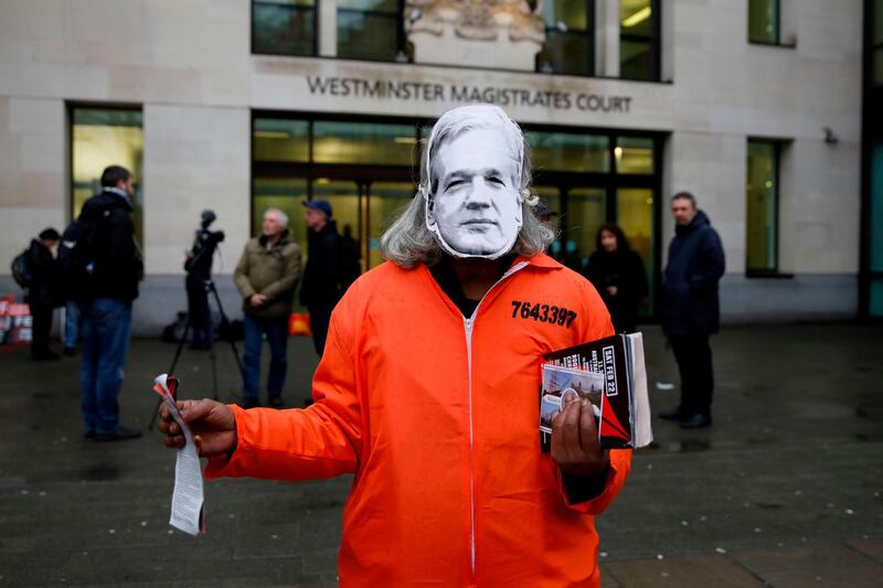 A protester wearing a Julian Assange mask, poses for a photograph as they support Wikileaks founder Julian Assange outside Westminster Magistrates Court in London on February 19, 2020, during Assange's remand hearing (via video-link) as he fights extradition to the United States. The main hearing in extradition proceedings against Wikileaks founder Julian Assange begins at the end of February. The United States has been demanding extradition of the 48-year-old Australian for years because of the publication of secret documents and violations of the anti-espionage law. / AFP / Tolga AKMEN
