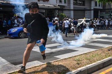 Protesters run after police fired tear gas to disperse them during a demonstration against the military coup in Yangon. AFP