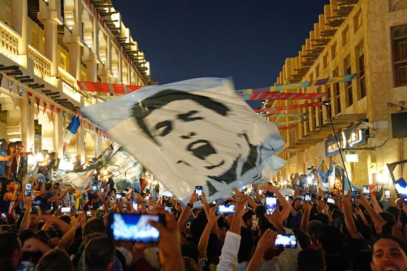 Argentina fans hold up a flag with the image of Diego Maradona.