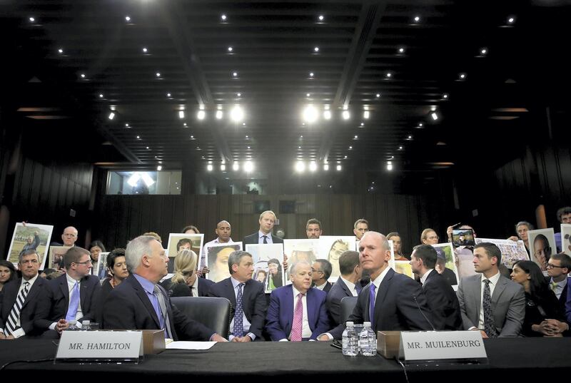 WASHINGTON, DC - OCTOBER 29: Family members of those who died aboard Ethiopian Airlines Flight 302 hold photographs of their loved ones as Dennis Muilenburg (R), President and CEO of the Boeing Company, and John Hamilton (L), Vice President and Chief Engineer of Boeing Commercial Airplanes, testify before the Senate Commerce Committee October 29, 2019 in Washington, DC. Muilenburg and Hamilton testified before the committee on "Aviation Safety and the Future of Boeing's 737 MAX."   Win McNamee/Getty Images/AFP