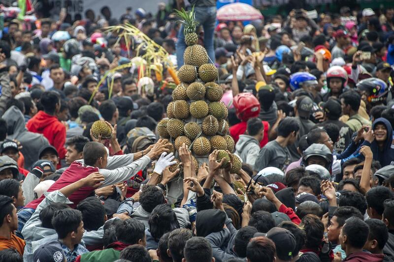 A crowd of people reach out to claim free durians, hailed as the "king of fruits" by fans, during the 'Kenduren' festival in Jombang, East Java. AFP