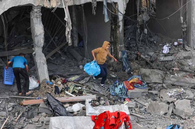 A Palestinian boy recovers items from the rubble of a building following Israeli strikes in the southern Gaza Strip. AFP