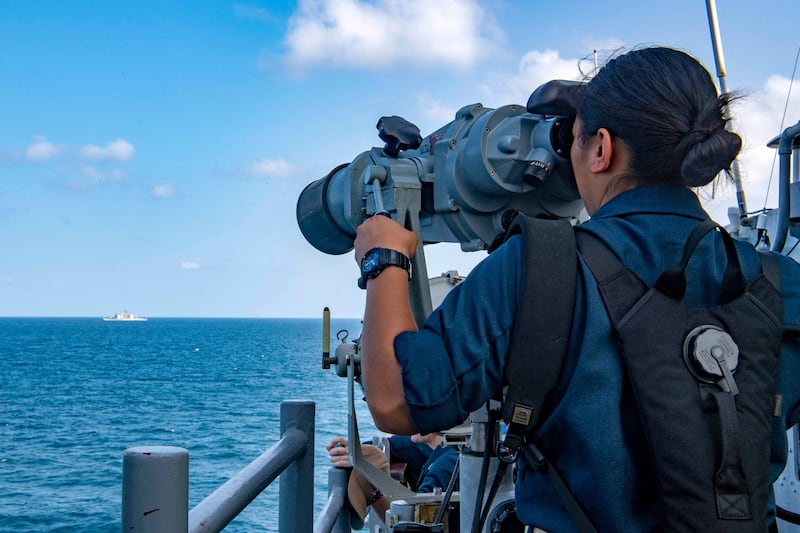 A US Navy personnel member looking through binoculars from the starboard bridge wing of the guided-missile cruiser USS Shiloh during a Strait of Hormuz transit with the guided-missile cruiser USS Monterey, on July 25.  (Rawad Madanat/US NAVY/AFP).