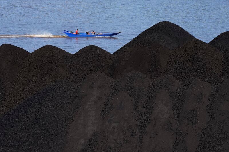 A boat cruises past a coal barge on Mahakam River in Samarinda, Indonesia. AP Photo