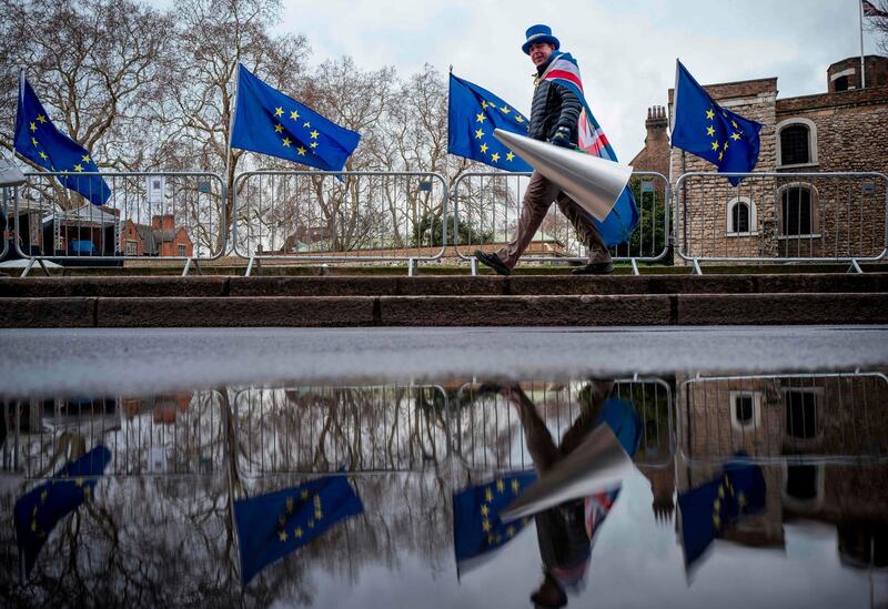 Anti-Brexit protester Steve Bray walks past EU and Union Flags on railings outside the Houses of Parliament in London on March 4, 2019. Britain's Prime Minister Theresa May has promised to return to parliament with an EU Withdrawl Bill for lawmakers to have a 'meaningful vote' by March 12. Unless there is a negotiated delay Britain will leave the EU on March 29.   / AFP / Tolga Akmen / Tolga Akmen
