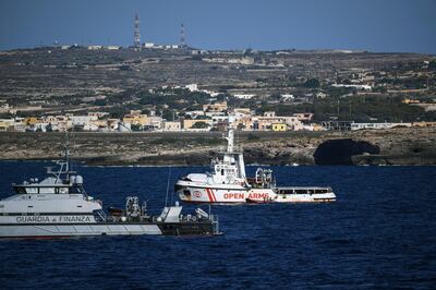 FILE - In this Aug. 19, 2019 file photo, an Italian Finance Police vessel patrols around the Open Arms vessel, with 107 migrants on board, as it is anchored off the Sicilian vacation and fishing island of Lampedusa, southern Italy. A judge in Sicily on Saturday, April 17, 2021, began weighing whether to put former Interior Minister Matteo Salvini on trial for having refused to let a Spanish migrant rescue ship dock in an Italian port in 2019, keeping the people at sea for days. (AP Photo/Salvatore Cavalli)