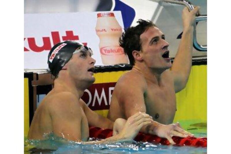 Ryan Lochte, right, and fellow American Scott Clary look up to see Lochte’s record-breaking time in the pool in Dubai last night.
