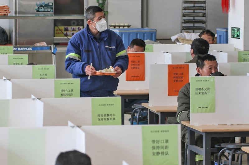 Workers have lunch at a dining hall using boards to separate people to prevent the spread of the new coronavirus in Yantai in China's eastern Shandong province. AFP