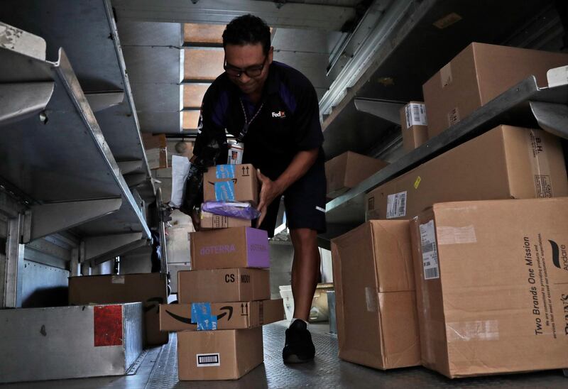 In this Tuesday, July 17, 2018 photo, a FedEx employee delivers packages in Miami. Amazon Prime Day was launched July 16 and and will be six hours longer than last year's and will launch new products. (AP Photo/Lynne Sladky)