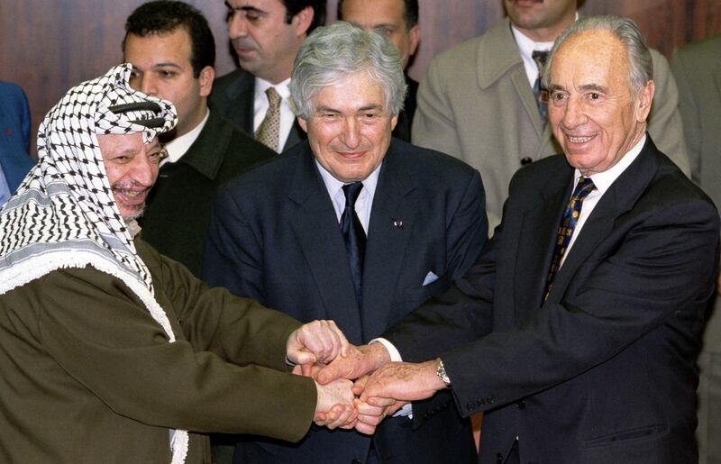 Former Palestinian president Yasser Arafat, Wolfensohn and former Israeli prime minister Shimon Peres join hands after signing agreements on January 20, 1998. Reuters