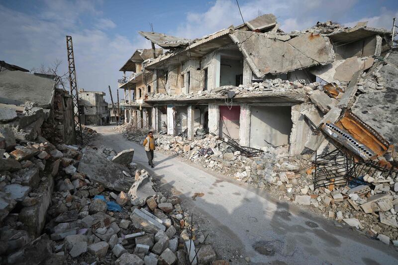 A Syrian man walks past damaged buildings in the town of Ihsim in the southern countryside of Idlib.  AFP