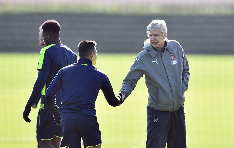 Alexis Sanchez pictured shaking hands with Arsenal manager Arsene Wenger during training on Monday. Glyn Kirk / AFP