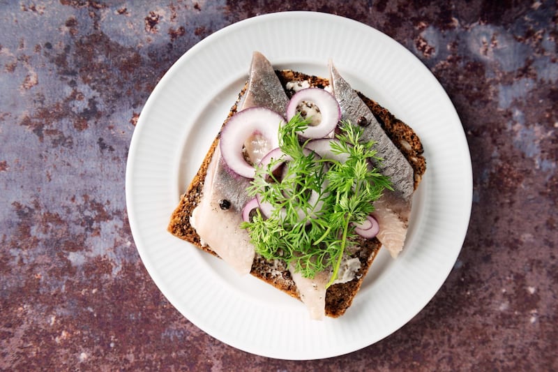 Traditional danish ‚Äúsmv?rrebrv?d‚Äù or open sandwich made with a slice of buttered rye bread, marinated herring, onion and dill. Colour, horizontal with some copy space.