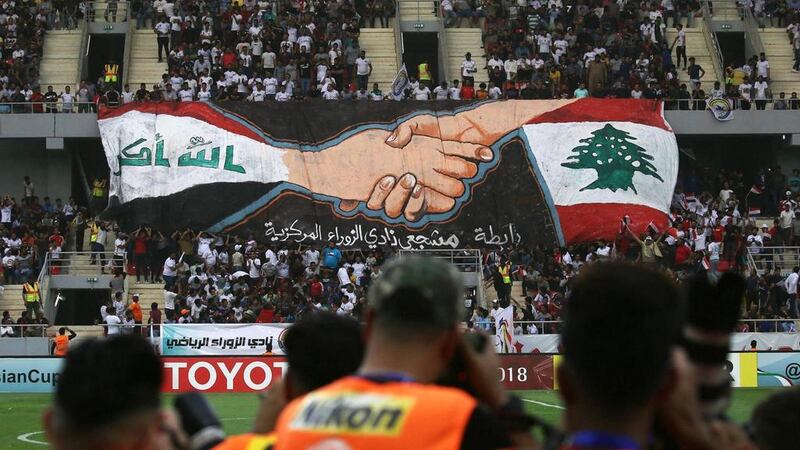 Football fans hold a large banner bearing the colours of the Lebanese, right, and Iraqi flag during the AFC Cup match between Al Zawraa and Al Ahed at the Karbala Sports City Stadium on April 10, 2018. Mohammed Sawaf / AFP